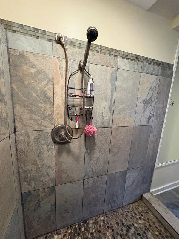 A tile shower installation with dual showerheads and built-in caddy in a bathroom renovation project.
