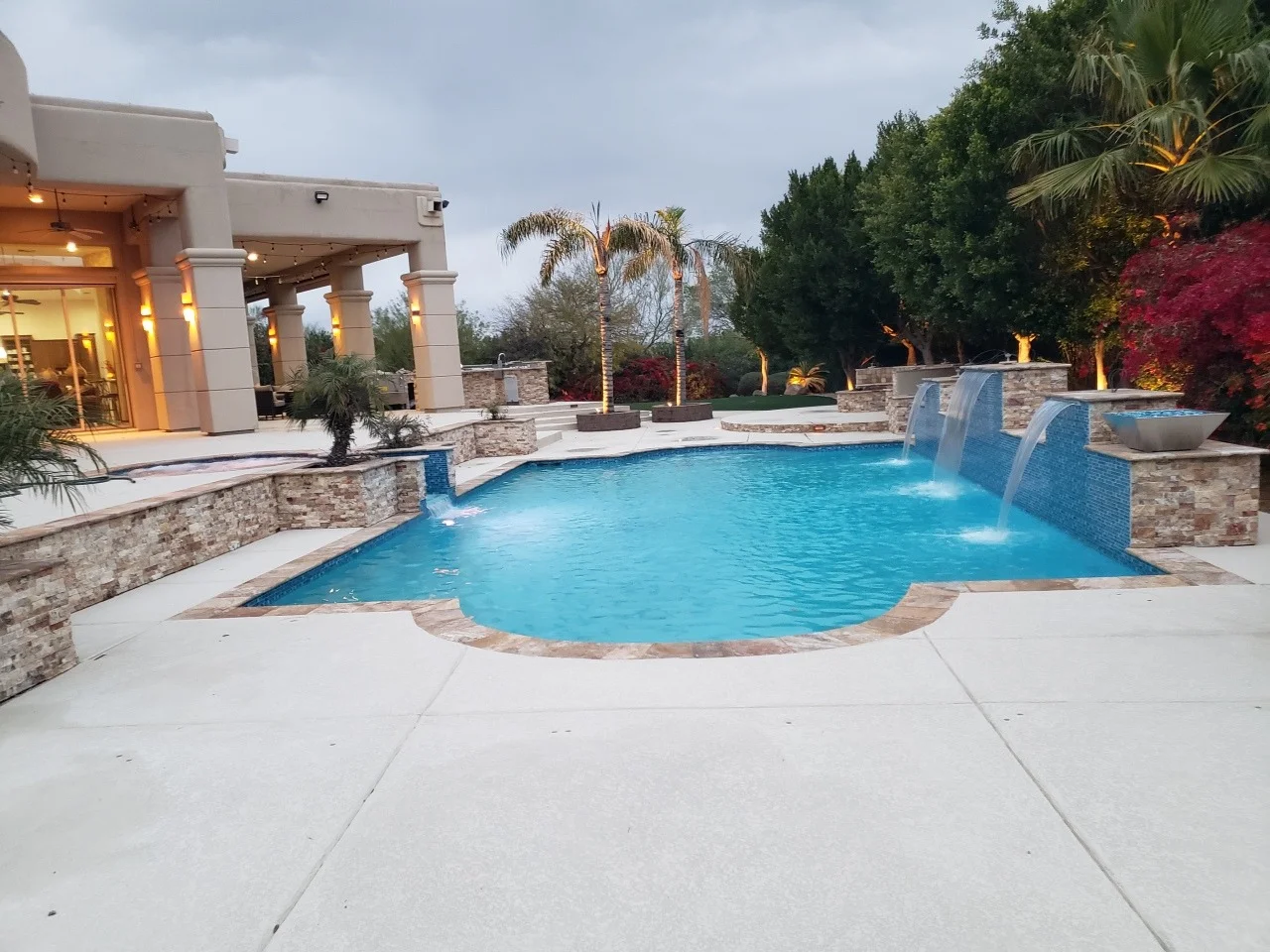 Custom resort-style swimming pool with stone waterfall features and curved design in a luxurious backyard entertainment area.