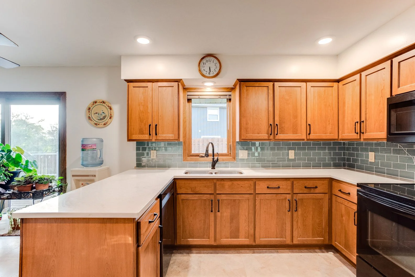 Modernized kitchen featuring oak cabinets, white quartz countertops, and a teal glass subway tile backsplash.