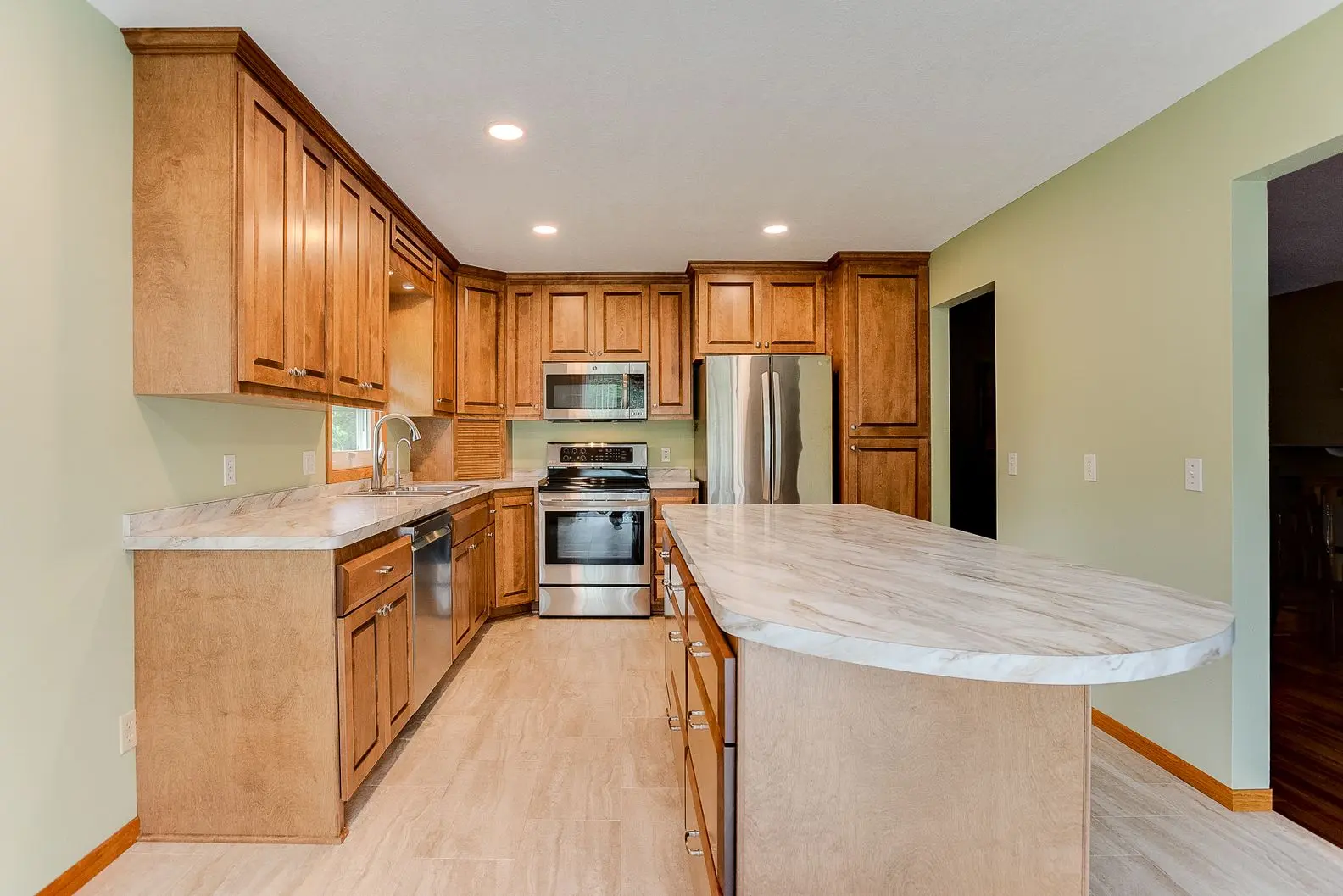 Modern kitchen featuring wood cabinets, stainless steel appliances, and a marble-patterned laminate island countertop.