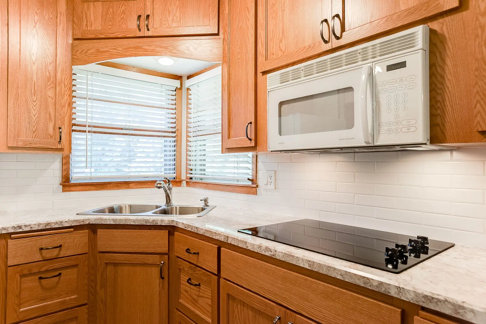 Modern kitchen with oak cabinets, white subway tile backsplash, and light marble-patterned countertops.
