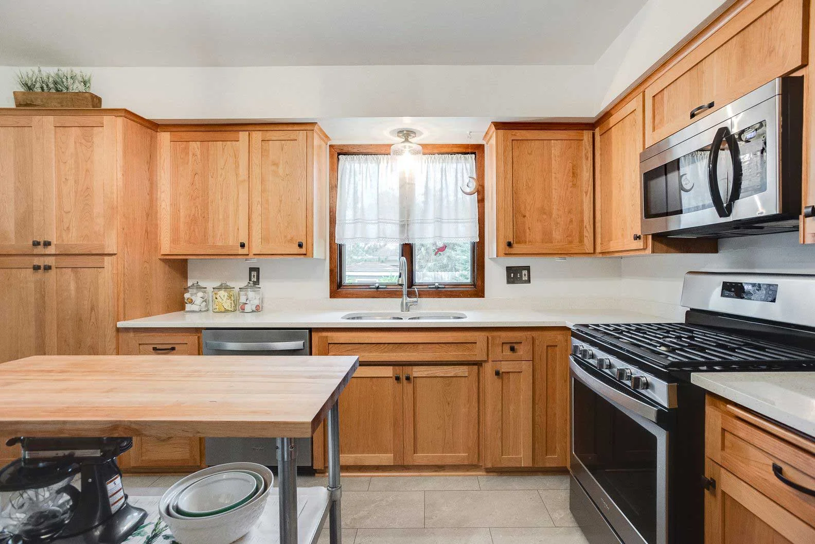 Modern kitchen featuring light oak cabinets, white quartz countertops, and stainless steel appliances with butcher block island.