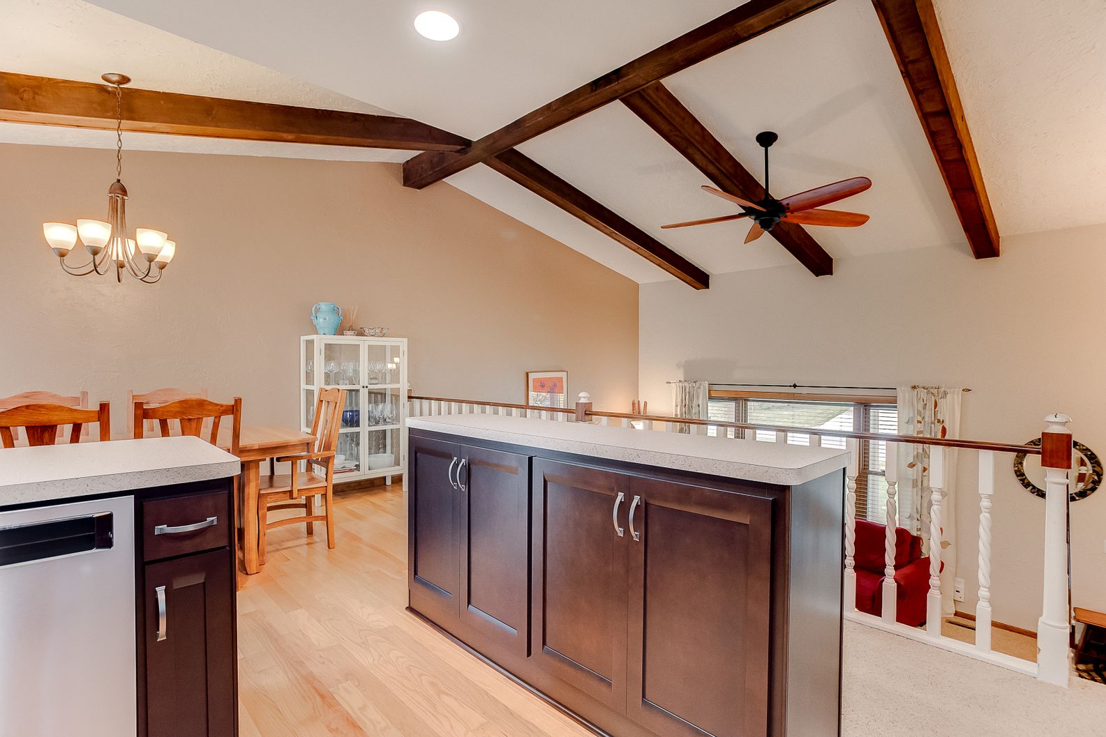 Dark wood kitchen island in a vaulted ceiling room with exposed dark wood beams and light flooring.