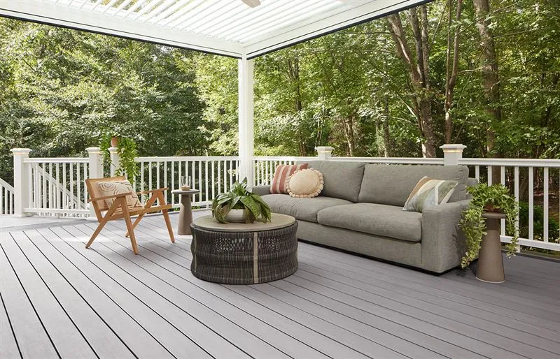 Modern composite deck featuring gray planks, a white railing, and a louvered pergola roof.