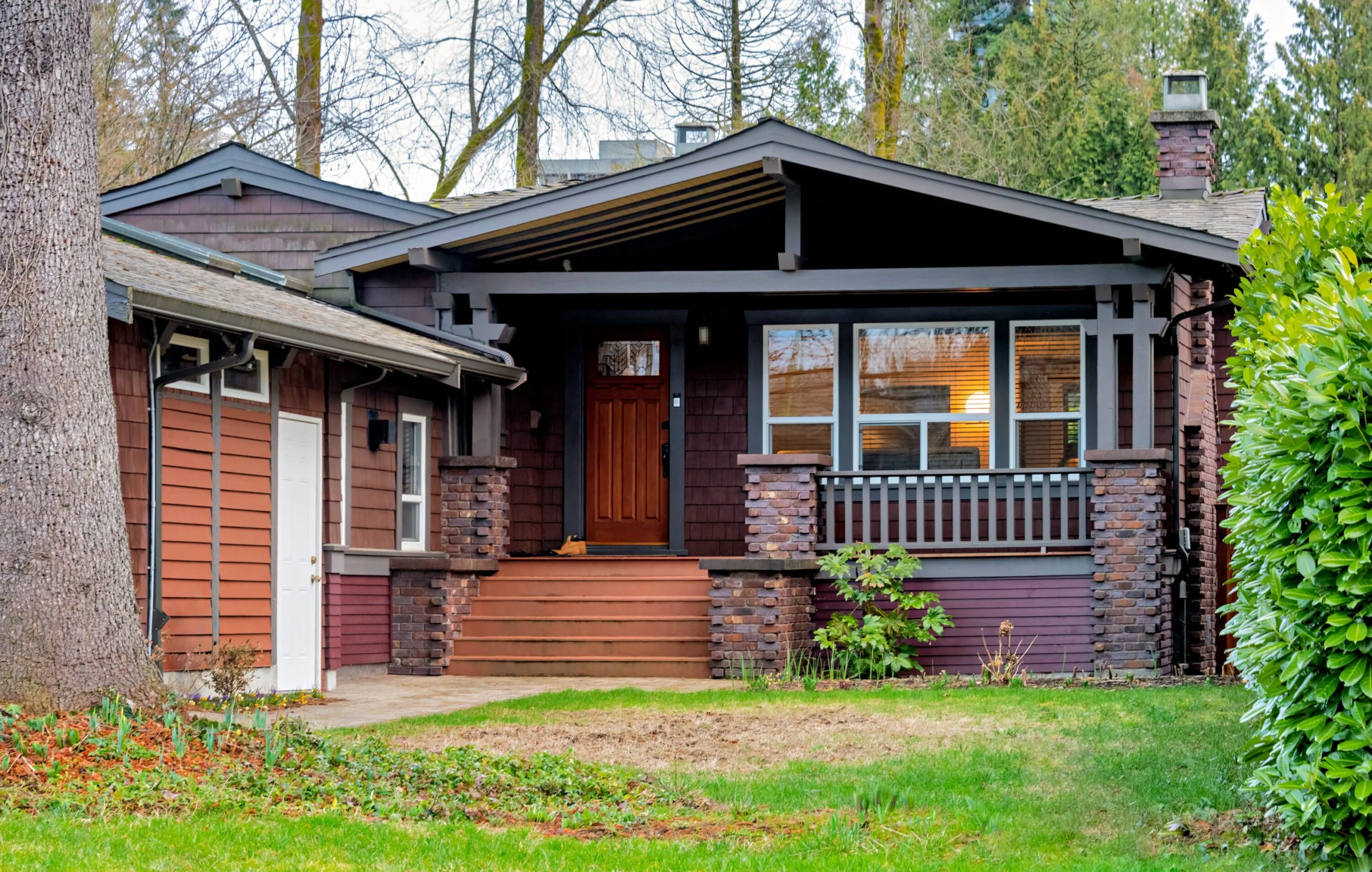 Modern craftsman bungalow with dark brown siding, cedar shake accents, and a large front porch.