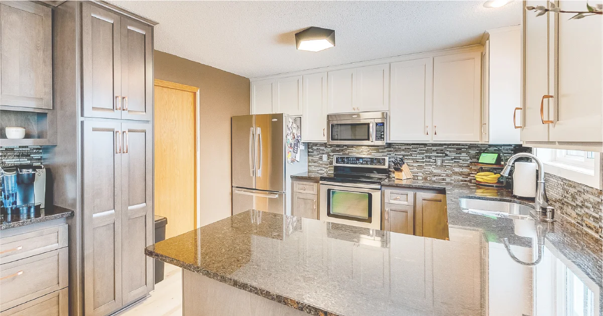 Modern kitchen remodel featuring dark granite countertops, stainless steel appliances, and two-tone shaker cabinets.