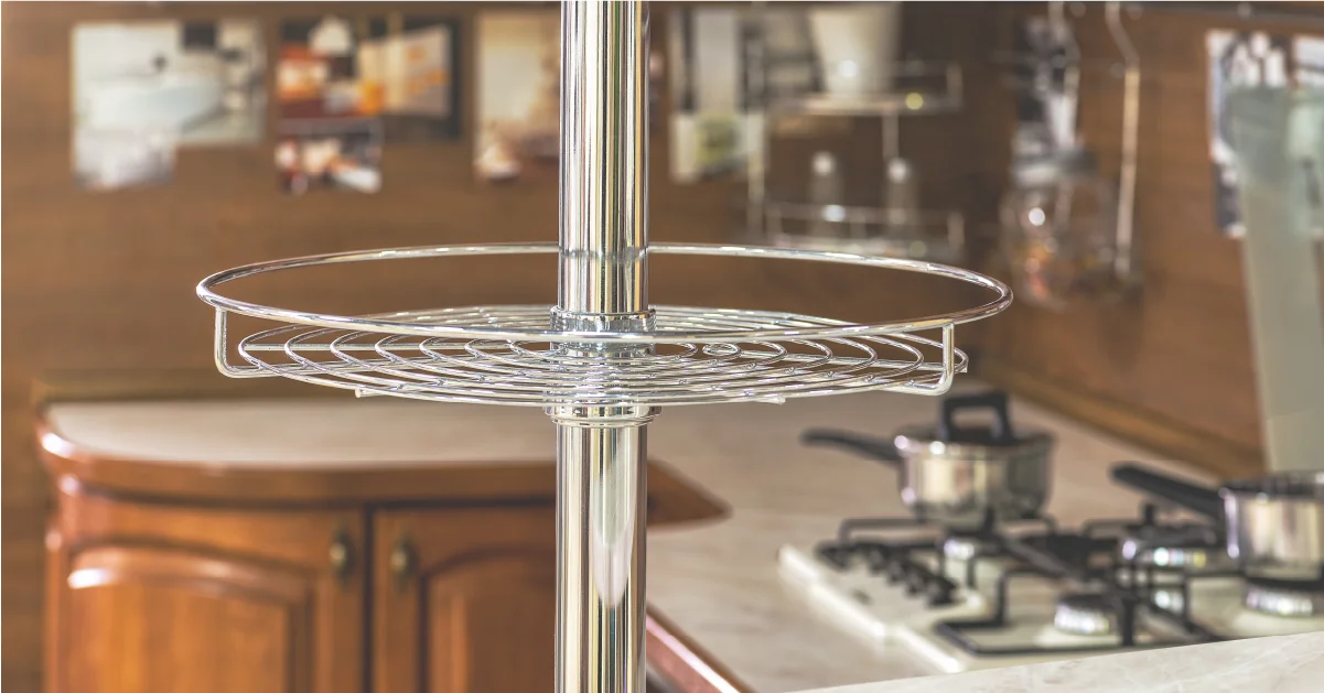 Chrome circular wire rotating shelf unit mounted on a vertical pole in a modern kitchen