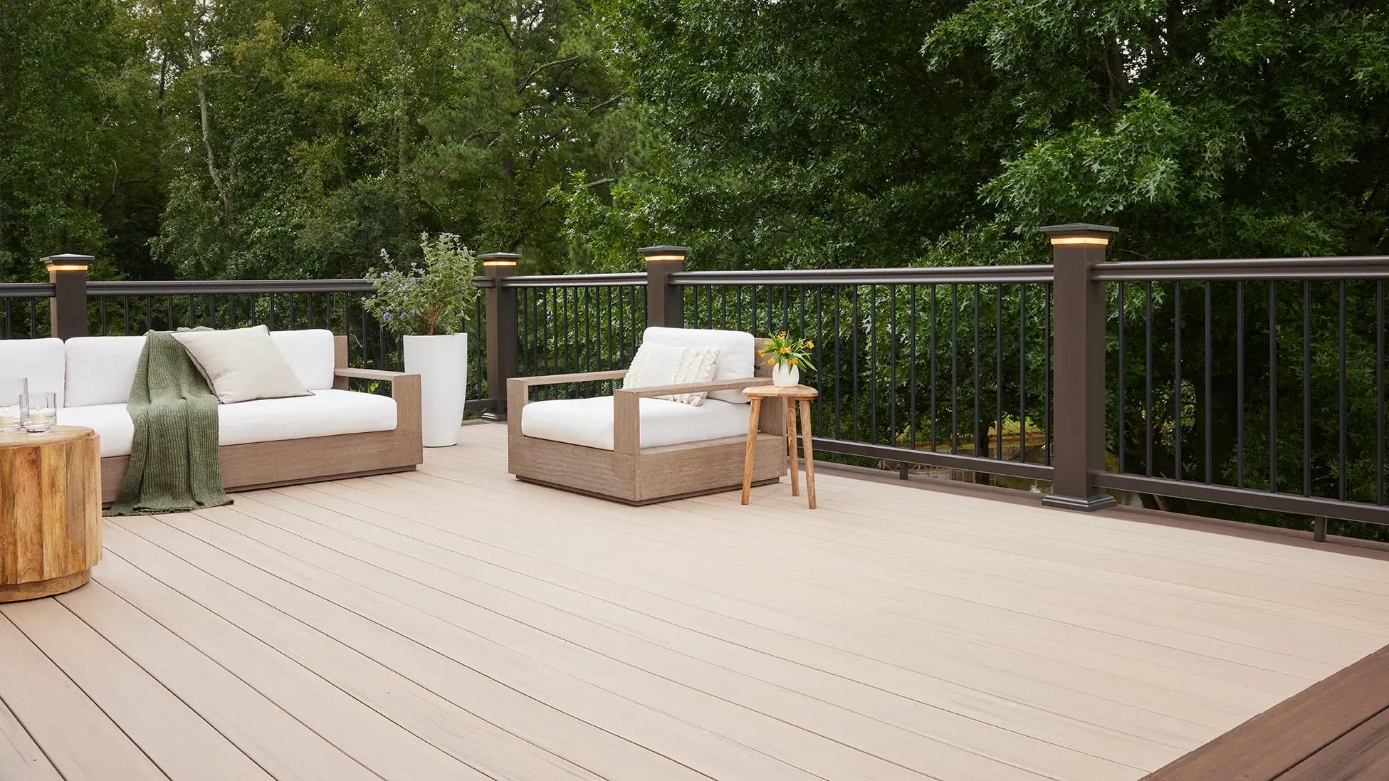 Modern composite deck with light wood-grain planks, dark railings, and integrated post cap lighting.