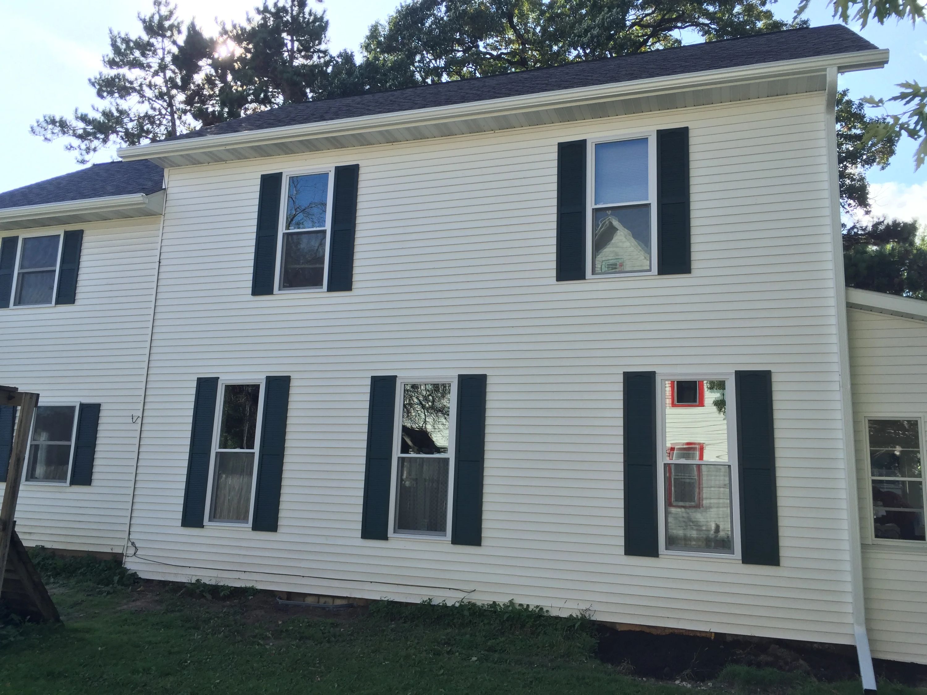 Black exterior shutters installed on multiple windows of a white vinyl-sided residential home.