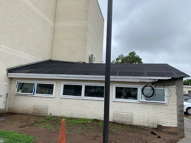Black retractable awning installed over multiple windows on the exterior of a commercial building.