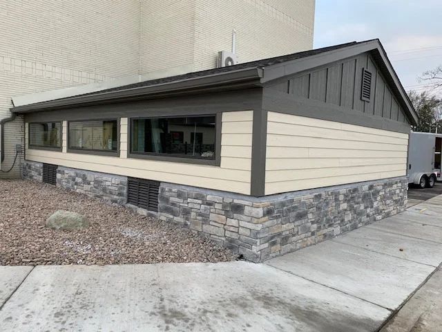 Modern siding and stone veneer on the exterior foundation and walls of a residential home addition or renovation.