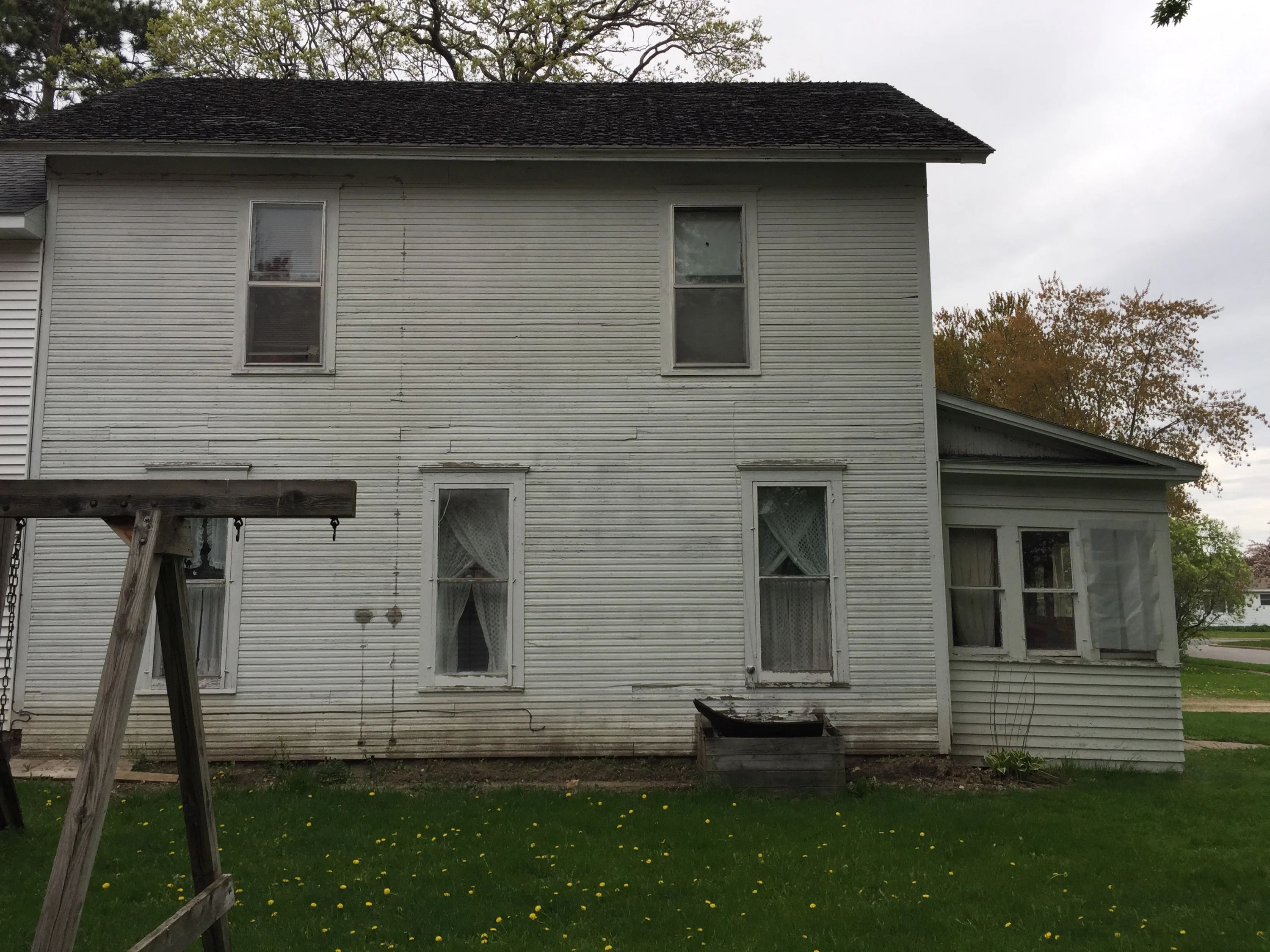 Windows with diamond-patterned glass panels on a white vinyl-sided residential home exterior.